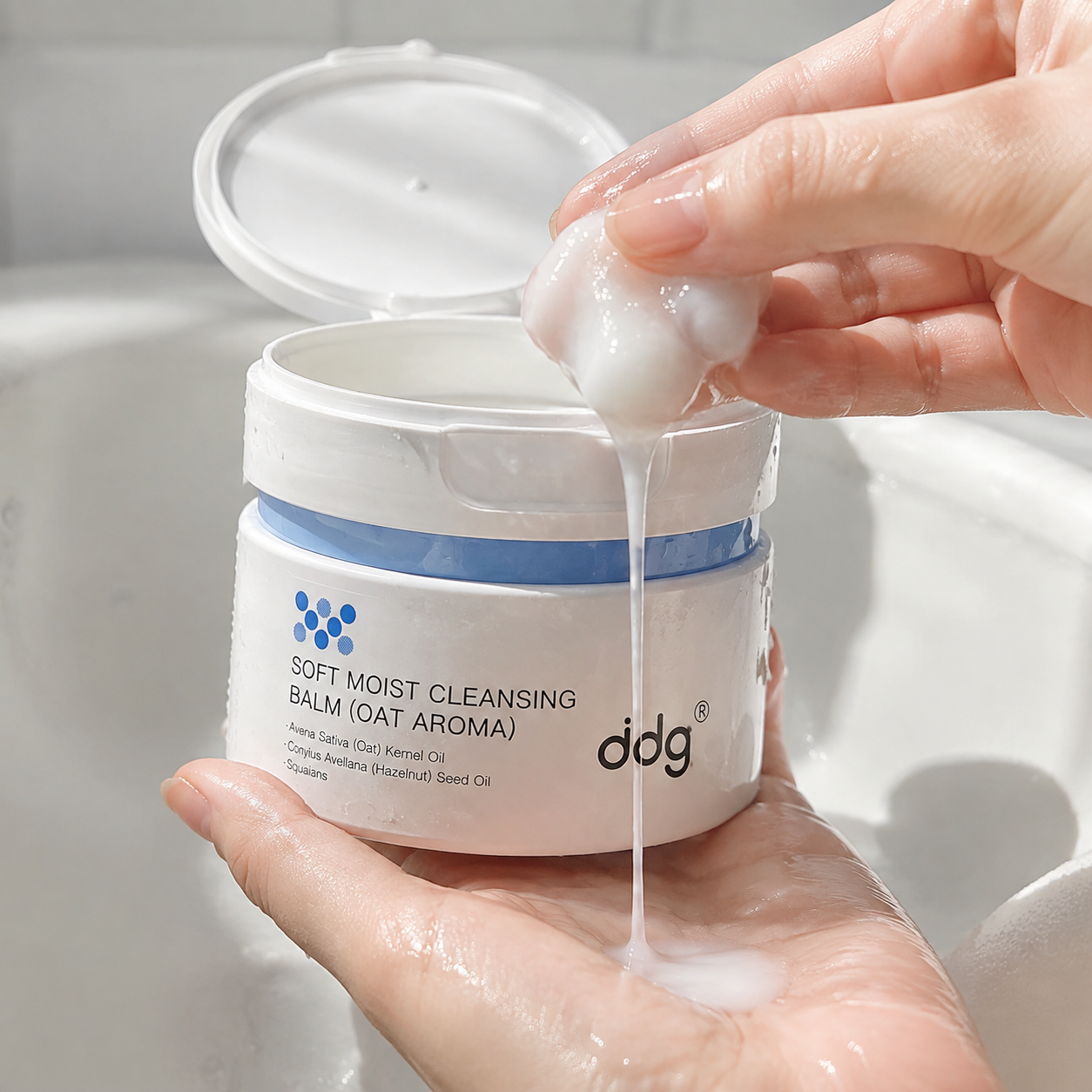 ddg Cleansing Balm jar with water droplets and a milky balm emulsion in hands